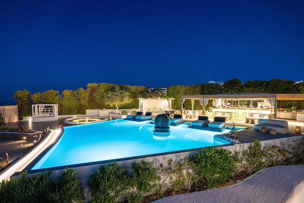 A swimming pool with lounge areas and a view of the surrounding landscape.