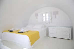 A bedroom with a bed, a bedside table, a wardrobe, and a window with shutters.