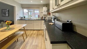 Una cocina moderna con una mesa de comedor de madera, encimera negra y armarios blancos.