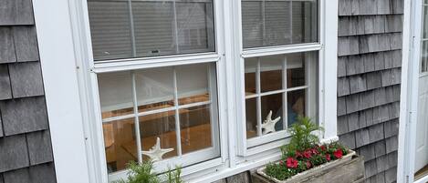 A building with a sign reading "CYGNET" above the windows. There are flower boxes with red flowers on the windowsill.