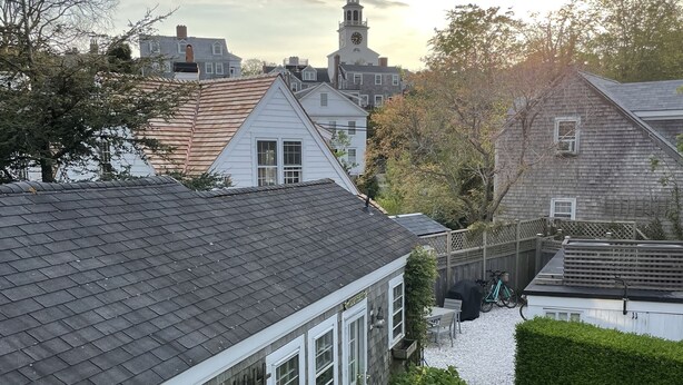 Ett bostadsområde med ett hus som har en veranda, ett trästaket och en välskött häck.