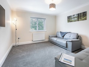 A modern living room with a grey sofa, a standing lamp, a radiator, and a window with blinds.