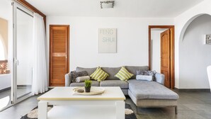 A modern living room with a sofa, a coffee table, and a sliding glass door. - 2-bedroom flat on Palm Mar beachfront with stunning view (Palm Mar)