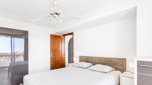 A bedroom with a bed, bedside table, lamp, wardrobe, and a ceiling fan. - 2-bedroom flat on Palm Mar beachfront with stunning view (Palm Mar)