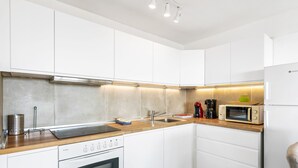 A modern kitchen with white cabinets, a wooden countertop, a built-in oven, a microwave, and a coffee maker. - 2-bedroom flat on Palm Mar beachfront with stunning view (Palm Mar)