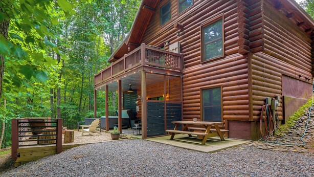Une cabane en rondins avec un porche, un espace salon extérieur et une allée en gravier.