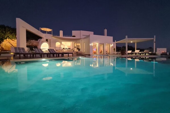 A modern poolside area with lounge chairs and a clear pool at dusk.