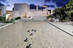 A courtyard with a modern building, a pergola, and a billiards table with balls.