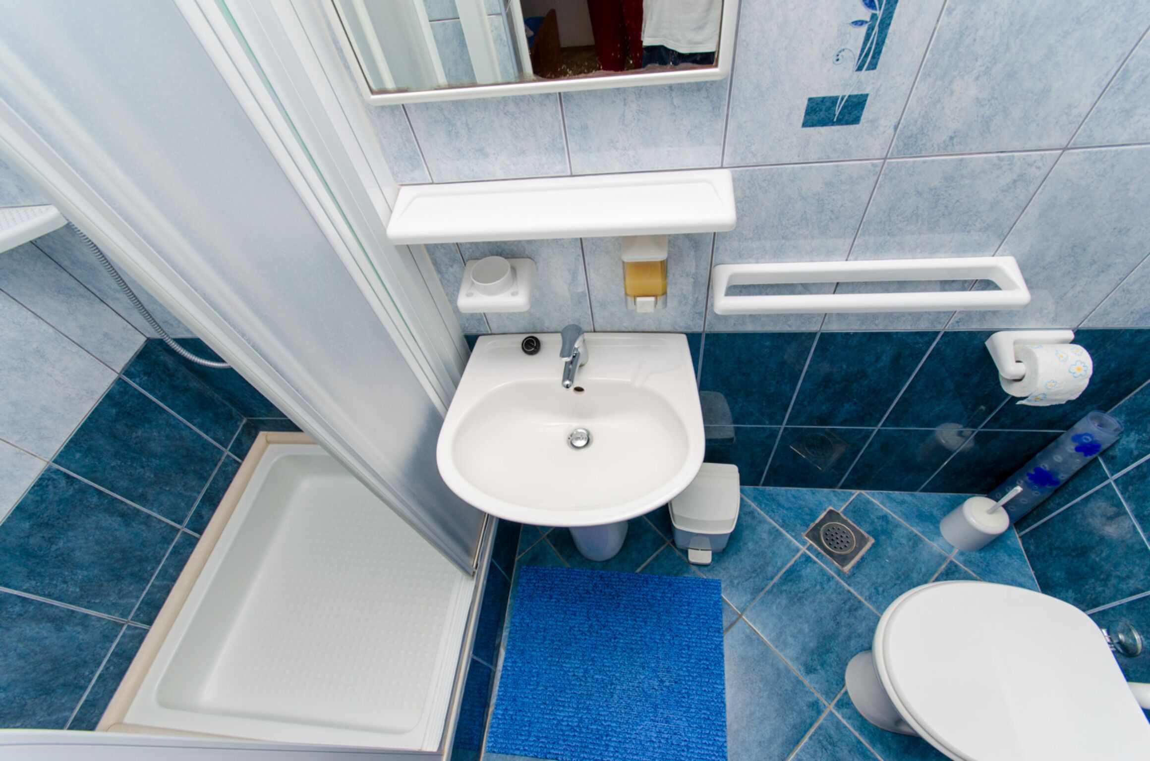 A bathroom with a white sink, a toilet, a blue shower, and a white bathtub.