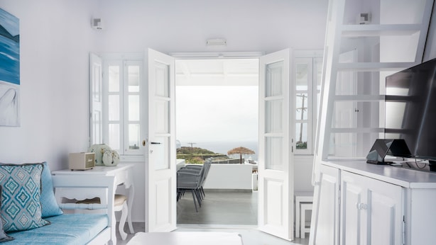 Ein modernes, weißes Wohnzimmer mit einem Balkon und Blick auf eine malerische Landschaft.