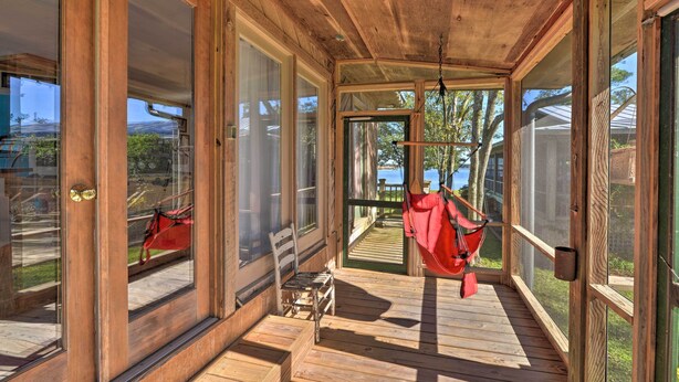 Une terrasse en bois avec un hamac, un banc et une vue sur l’extérieur.