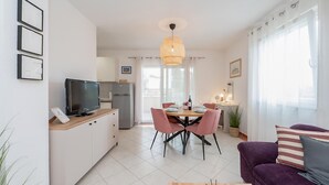 A modern living room with a TV, dining area, and purple sofa. - 2 bedroom nice apartment in Rogoznica (Rogoznica)