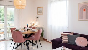 A dining area with a round table, pink chairs, and a bottle of wine. There is a sofa with cushions and a small table with a plant. - 2 bedroom nice apartment in Rogoznica (Rogoznica)