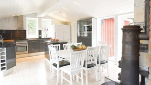 Een moderne keuken met een centraal eiland, witte stoelen en een fornuis.