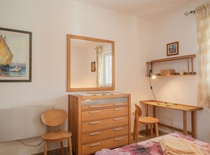 Ein Schlafzimmer mit einem hölzernen Schminktisch, einem Stuhl, einem Schreibtisch und einem Bett.