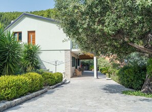 A building with a stone facade, a covered porch, and a paved pathway leading to it.