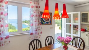 A dining area with a view of the sea, a table with chairs, and red pendant lights. - Vacation House Marija -Two Bedroom Holiday Home with Terrace and Sea View (Korcula)