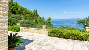 A stone-paved terrace with a stone wall, a potted plant, and a view of the sea. - Vacation House Marija -Two Bedroom Holiday Home with Terrace and Sea View (Korcula)
