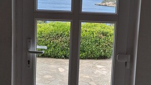 A door with a view of a stone patio and a cat sitting inside. - Vacation House Marija -Two Bedroom Holiday Home with Terrace and Sea View (Korcula)