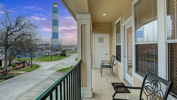 A balcony with a view of a street, a bench, and a door. - Luxury vacation Kemah, TX condo. Bars and restaurants within walking distance. (Kemah)