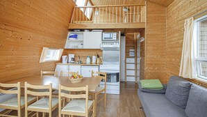 A compact wooden cabin with a dining area, kitchenette, and a loft bedroom. - Beach front home in Hvide Sande (Hvide Sande)