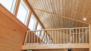 A wooden balcony with a metal railing, large windows, and a sloped ceiling. - Beach front home in Hvide Sande (Hvide Sande)