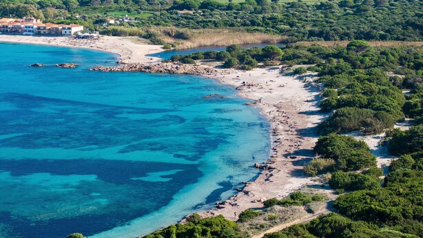An aerial view of a coastal area with a beach, rocky shoreline, and dense greenery. - Vignola Baia dei Mirti B4 (Vignola Mare -SS-)