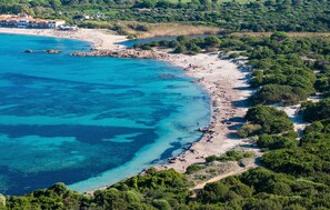 An aerial view of a coastal area with a beach, rocky shoreline, and dense greenery. - Vignola Baia dei Mirti B4 (Vignola Mare -SS-)