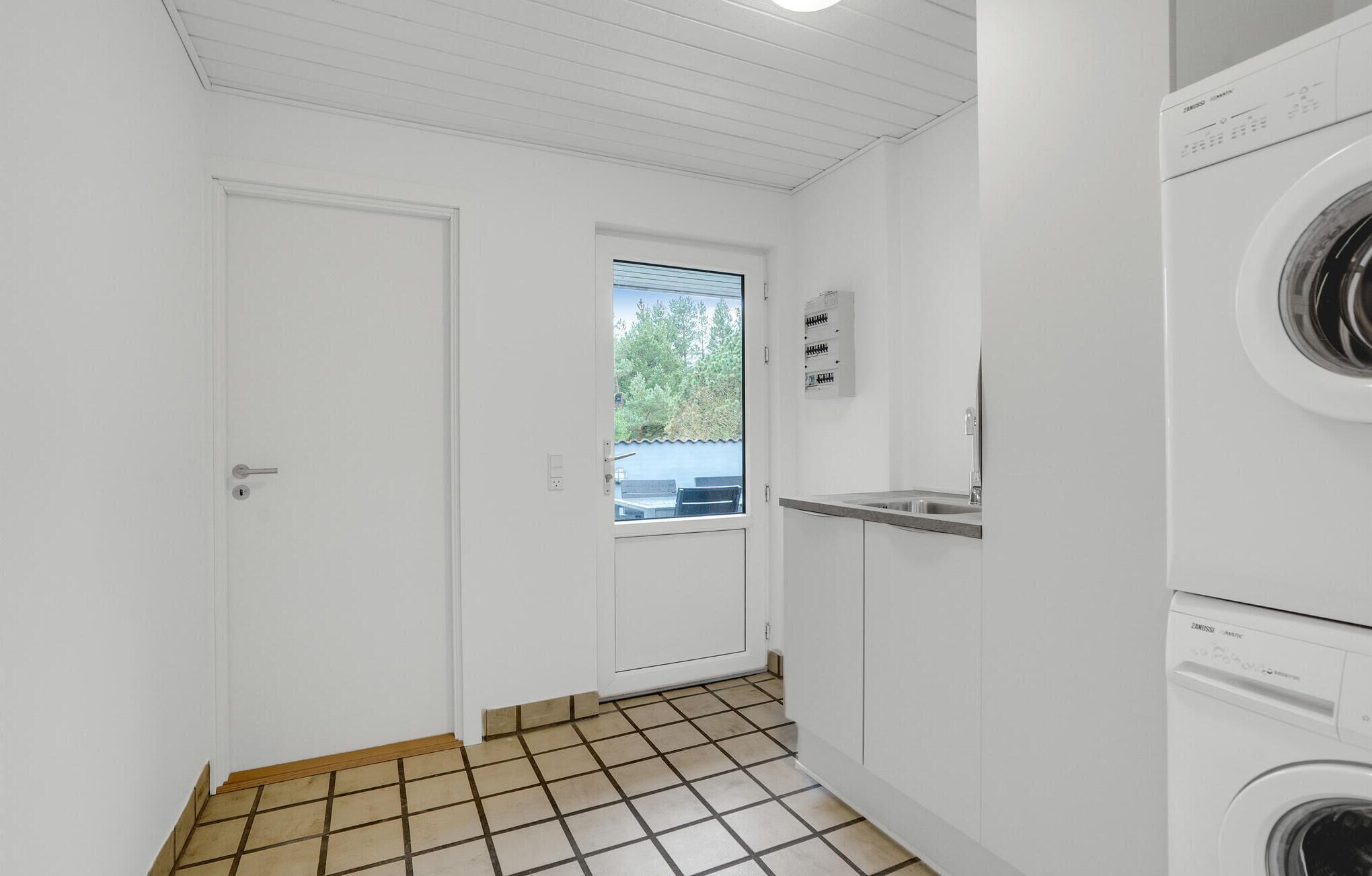 Ein Waschraum mit Waschmaschine, Trockner und einem Fenster mit Blick auf Grünflächen.