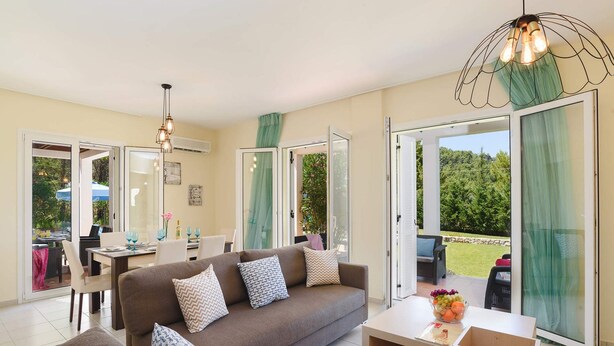 Ein Wohnzimmer mit einer Couch, einem Esstisch und einem Balkon mit Blick auf Bäume.