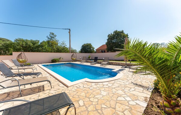 Une piscine avec des chaises longues et une terrasse en pierre.