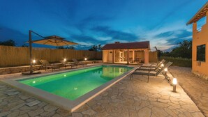 Une piscine avec des chaises longues et un espace patio couvert.