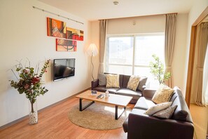 A living room with a sofa, coffee table, TV, and artwork on the wall.