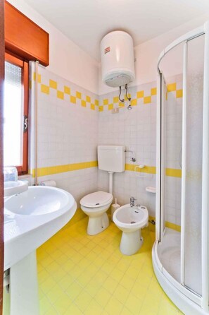 A bathroom with two sinks, a toilet, a bidet, and a shower.