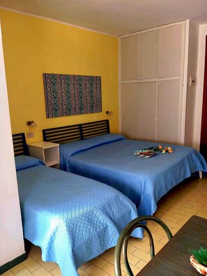 A room with two beds, a wardrobe, and a wall hanging.