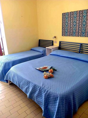A room with two beds, a small table, and a wall with a decorative pattern.