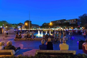A public square with a fountain, benches, and people.