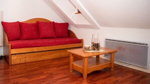 Ein gemütliches Zimmer mit einer Holzsofa, einem kleinen Holztisch und einer Heizung.