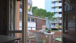 Ein Balkon mit Tisch, Stühlen, einer Topfpflanze und Blick auf ein Gebäude und Bäume.