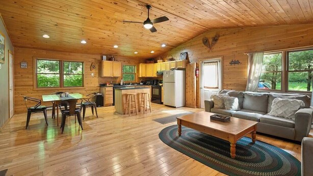 Interior de una cabaña de madera con comedor, cocina y sala de estar.