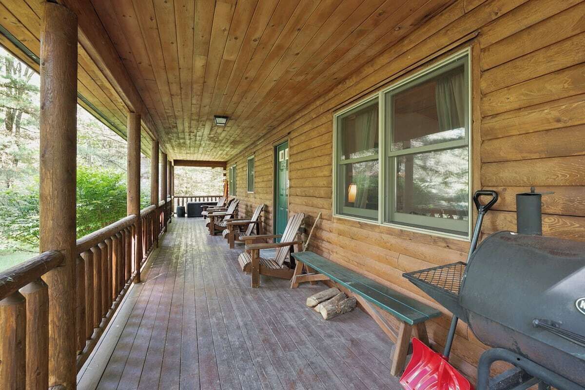 Une véranda en bois avec des bancs et un barbecue.