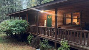 Una cabaña de troncos con un porche, una puerta verde y un letrero que dice "FRIE".