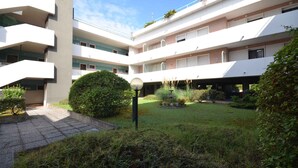 Un edificio de varios pisos con un patio que cuenta con una farola, una pequeña fuente y diversas plantas.