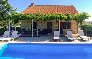 Ein Haus aus Stein mit einem Ziegeldach, einem Pool und Sitzgelegenheiten im Freien.