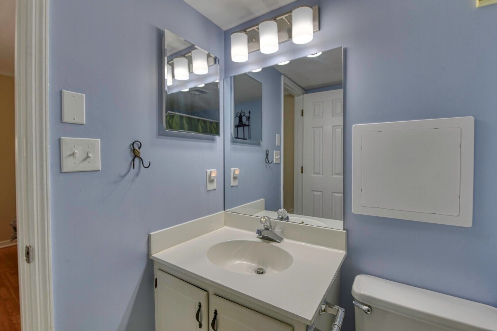 A bathroom with a sink, mirror, and light fixtures.