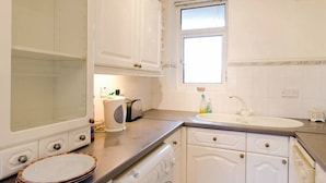 Eine Küche mit weißen Schränken, einem eingebauten Backofen, einem Spülbecken und einem Fenster.