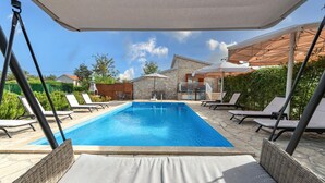Une piscine rectangulaire avec des chaises longues et des parasols.