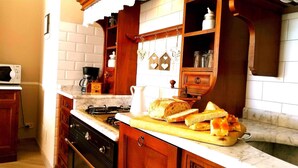 Une cuisine équipée d’une cuisinière à gaz, d’une machine à café et d’un panier à pain posé sur le comptoir.