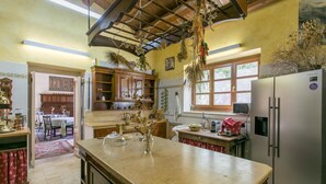 Eine Küche mit einer großen Kochinsel, Holzschränken, einem Kühlschrank und einem Essbereich mit Tisch und Stühlen.