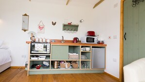 Uma cozinha compacta com micro-ondas, chaleira e mini-geladeira.